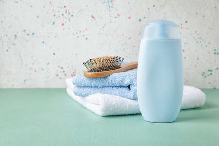 Bottle of shampoo, towels and brush on color backgroundの写真素材