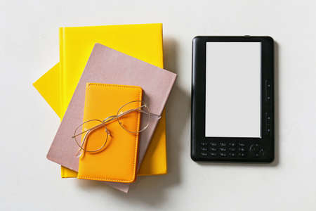 E-reader with notebooks and eyeglasses on light backgroundの写真素材