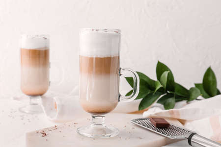 Glass cup of tasty latte on light backgroundの写真素材