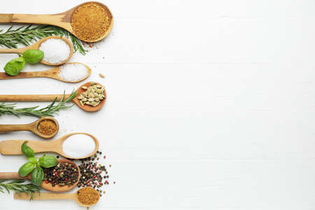 Spoons with different spices and herbs on light wooden backgroundの写真素材