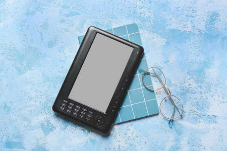 E-reader, notebook and eyeglasses on color backgroundの写真素材