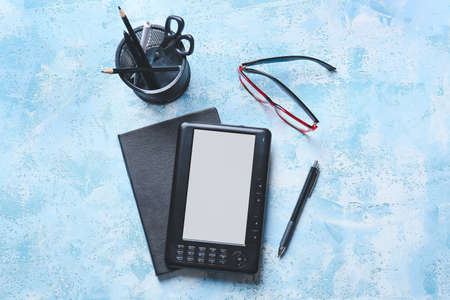 E-reader, stationery and eyeglasses on color backgroundの写真素材