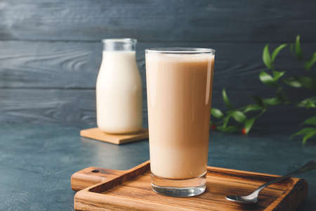 Glass of tasty latte on color wooden backgroundの写真素材