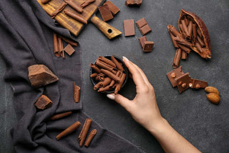 Female hand with chocolate curls on dark backgroundの写真素材