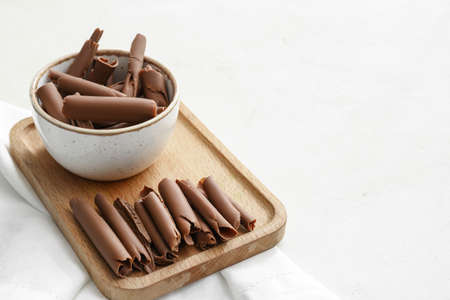 Bowl with delicious chocolate curls on light backgroundの写真素材