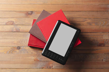 E-reader and books on wooden background