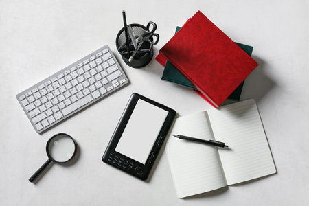Composition with e-reader, computer keyboard and stationery on light backgroundの写真素材