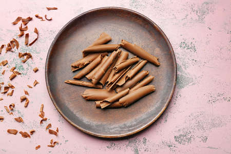 Plate of tasty chocolate curls on color backgroundの写真素材