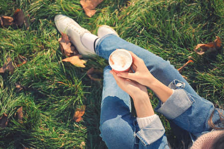 Woman with takeaway cup of tasty latte in parkの写真素材