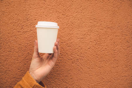 Woman with takeaway cup of tasty latte on color backgroundの写真素材