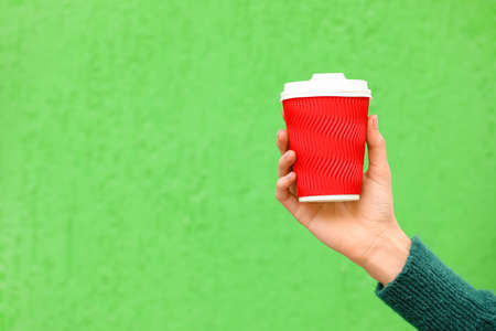 Woman with takeaway cup of tasty latte on color backgroundの写真素材