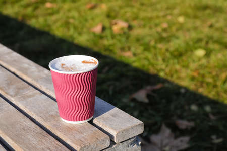 Takeaway cup of tasty latte on bench outdoorsの写真素材
