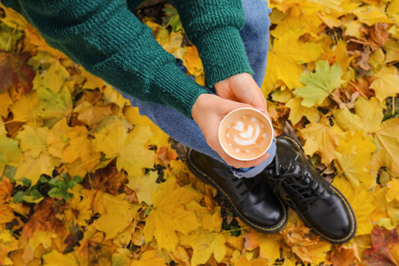 Woman with takeaway cup of tasty latte in park