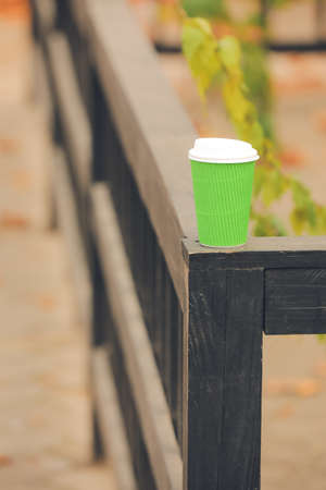 Takeaway cup of tasty latte on fence, outdoorsの写真素材