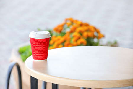 Takeaway cup of tasty latte on table outdoorsの写真素材