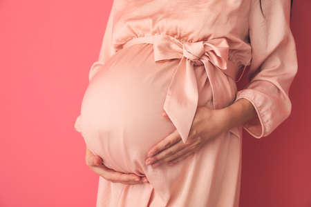 Pregnant young woman on color backgroundの写真素材