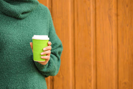 Woman with takeaway cup of tasty latte near wooden wallの写真素材