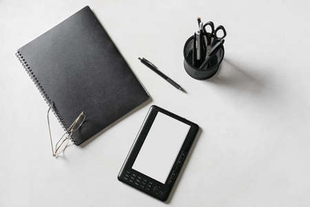 E-reader with notebook, stationery and eyeglasses on light backgroundの写真素材