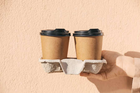 Woman holding takeaway cups of tasty latte on color background, closeupの写真素材