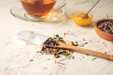 Tea bag and spoon with dry leaves on light backgroundの写真素材