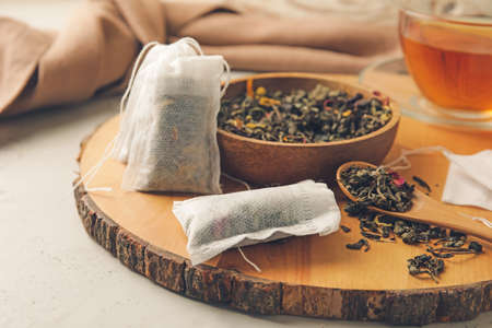 Tea bags and bowl with dry leaves on light backgroundの写真素材