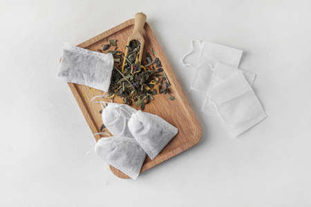 Tea bags and scoop with dry leaves on light backgroundの写真素材
