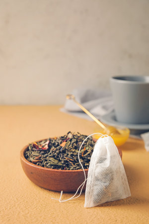 Tea bag and bowl with dry leaves on color backgroundの写真素材