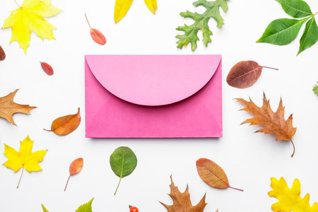 Envelope and autumn leaves on white background