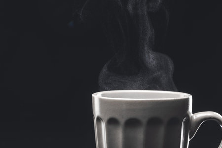 Cup of hot coffee on dark background, closeup