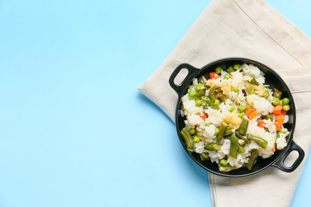 Frying pan with cooked vegetables and rice on color backgroundの写真素材