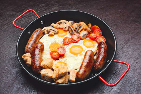 Frying pan with tasty breakfast on dark backgroundの写真素材