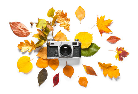 Beautiful autumn composition with leaves and photo camera on white backgroundの写真素材