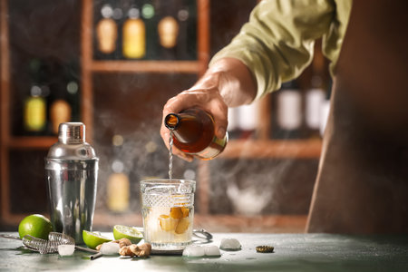 Bartender pouring fresh ginger beer into glass on table in barの写真素材