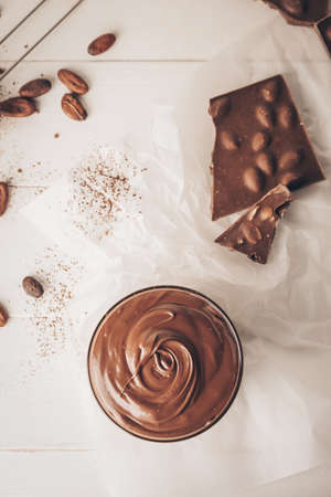 Bowl of tasty melted chocolate on light wooden background