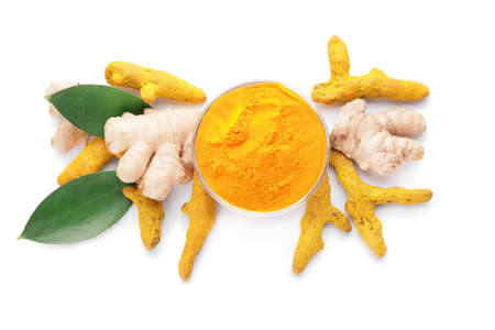 Bowl with turmeric powder and roots on white backgroundの写真素材
