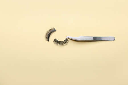 Tweezers with false eyelashes on color backgroundの写真素材