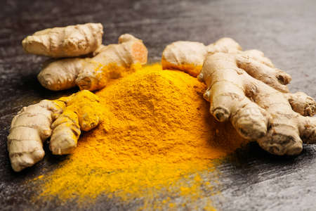 Turmeric powder and roots on dark backgroundの写真素材