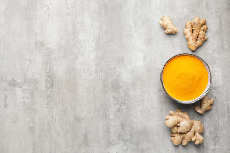 Bowl with turmeric powder and roots on grunge backgroundの写真素材