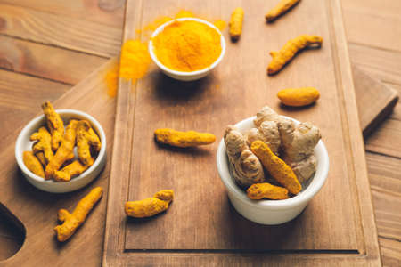 Bowls with turmeric roots on wooden backgroundの写真素材