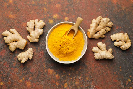 Bowl and scoop with turmeric powder on grunge backgroundの写真素材