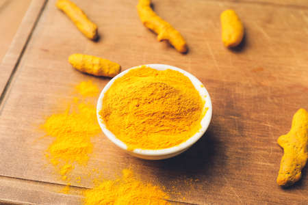 Bowl with turmeric powder and roots on board, closeupの写真素材