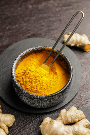 Bowl with turmeric powder on dark backgroundの写真素材