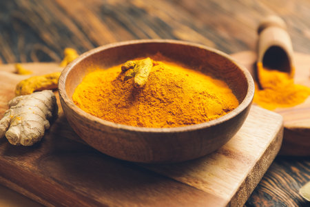 Bowl with turmeric powder on wooden backgroundの写真素材