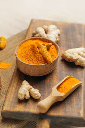 Bowl and scoop with turmeric powder on chopping boards, closeupの写真素材