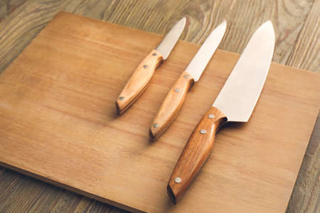 Board with knives on wooden backgroundの写真素材