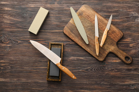 Board with set of knives and sharpening stone on wooden backgroundの写真素材