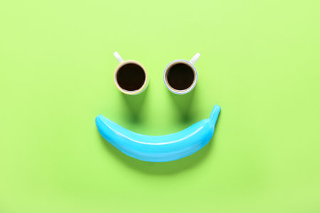 Creative composition with painted banana and cups of coffee on color backgroundの写真素材
