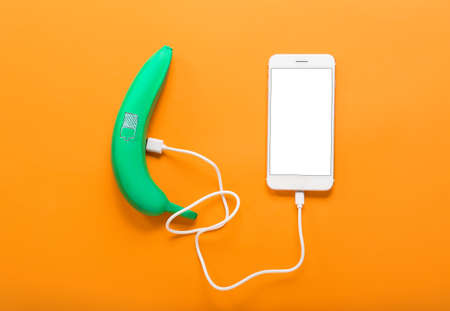 Creative composition with painted banana and mobile phone on color background