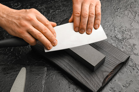Man sharpening knife on dark backgroundの写真素材