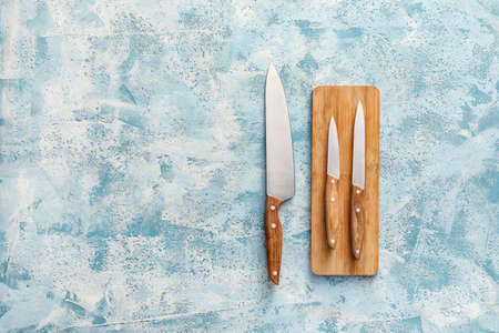 Board with knives on color background